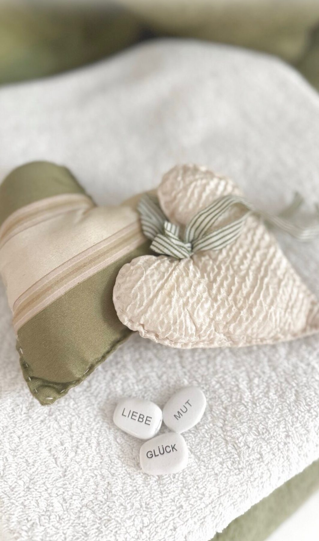 Duftherzen und Steine mit den Worten Liebe, Mut, Glück auf einem Handtuch